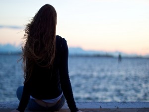 Chica de espaldas contemplando un lago