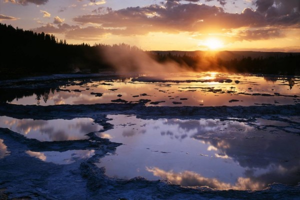 El sol del amanecer iluminando una gran fuente de agua caliente (Yellowstone)