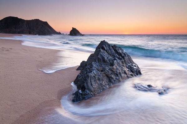 Roca en la playa bañada por las olas