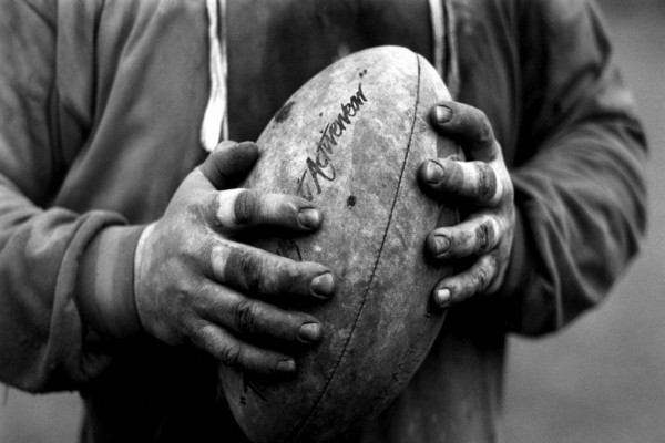 Manos de hombre sosteniendo un balón de rugby