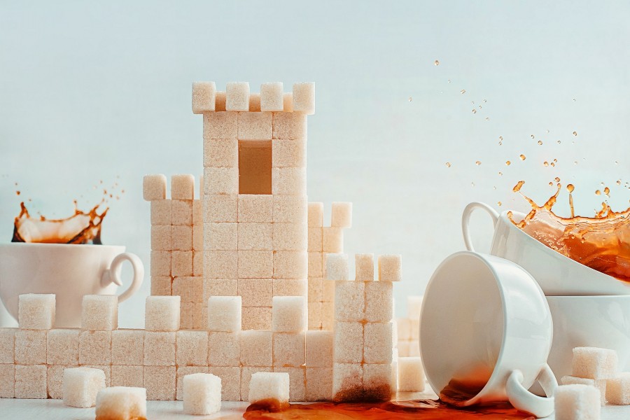 Tazas de café junto a un castillo de cubos de azúcar