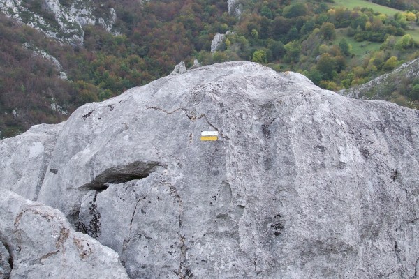 Señal de ruta blanca y amarilla en una roca