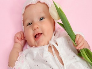 El bebé de la sonrisa sosteniendo un tulipán