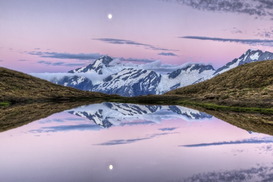 Luna y montañas reflejadas en un lago