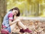 Chica sentada sobre hojas otoñales