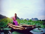 Mujer sentada en un bote sosteniendo flores de loto