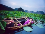 Chica durmiendo en un bote entre flores de loto