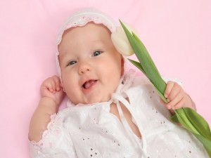 Hermoso bebé sosteniendo un tulipán