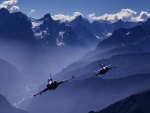 Dos aviones de combate volando entre montañas