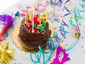 Postal: Pastel de chocolate con velas de cumpleaños y serpentinas