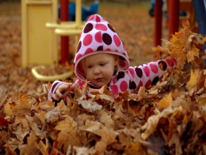 Niña jugando con las hojas de otoño