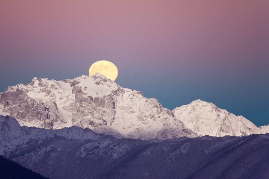 Gran luna tras la cima de una montaña