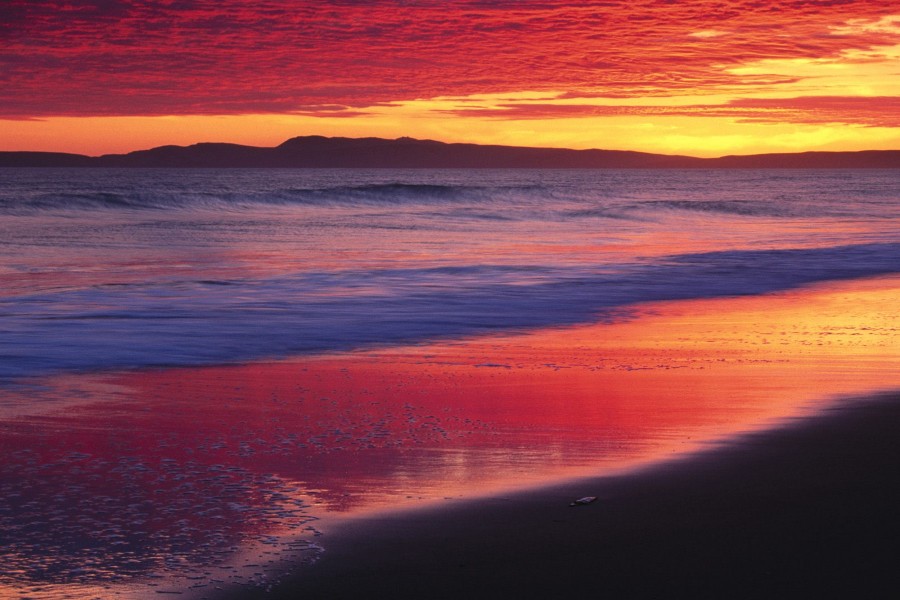 Los colores del amanecer reflejados en la orilla