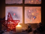 Vela y estrella de Navidad junto a una ventana
