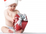 Bebé tratando de abrir un regalo de Navidad
