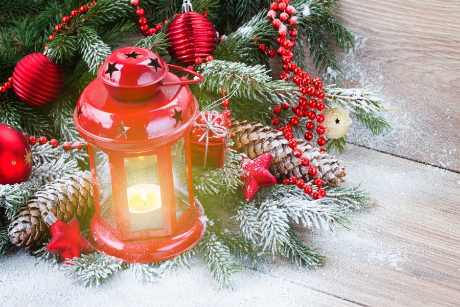 Farol con una vela encendida junto a un árbol de Navidad