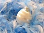Bola blanca de Navidad sobre plumas azules