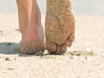 Dos pies que caminan en la arena bajo el sol de verano