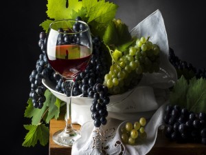Postal: Uvas blancas y negras junto a una copa de vino tinto