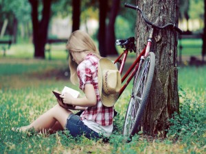 Chica leyendo junto a una bicicleta