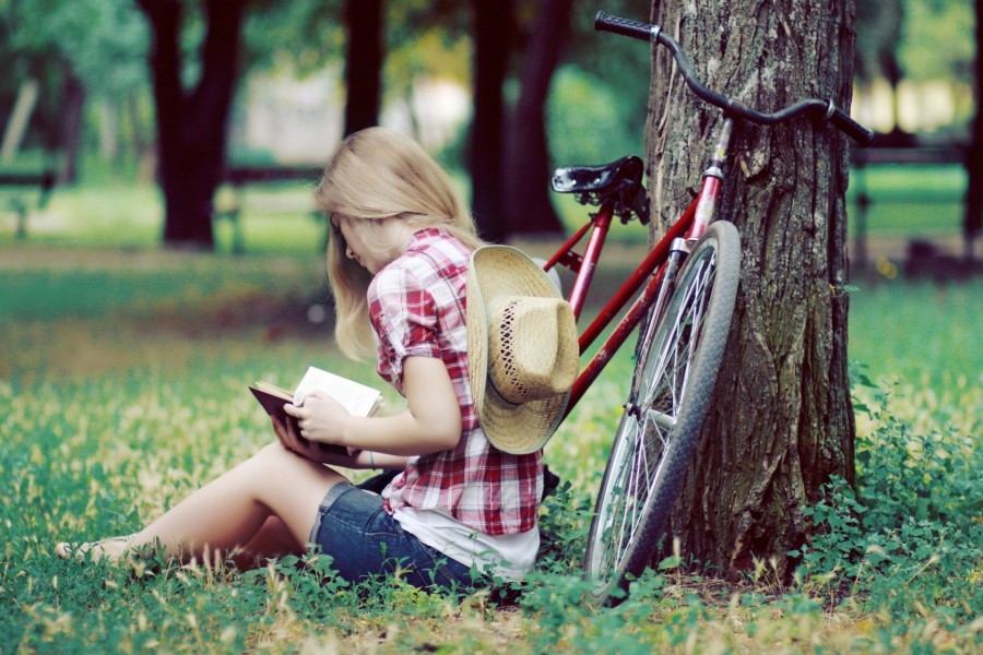 Chica leyendo junto a una bicicleta