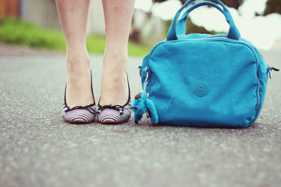 Las piernas de una chica junto a un bolso azul