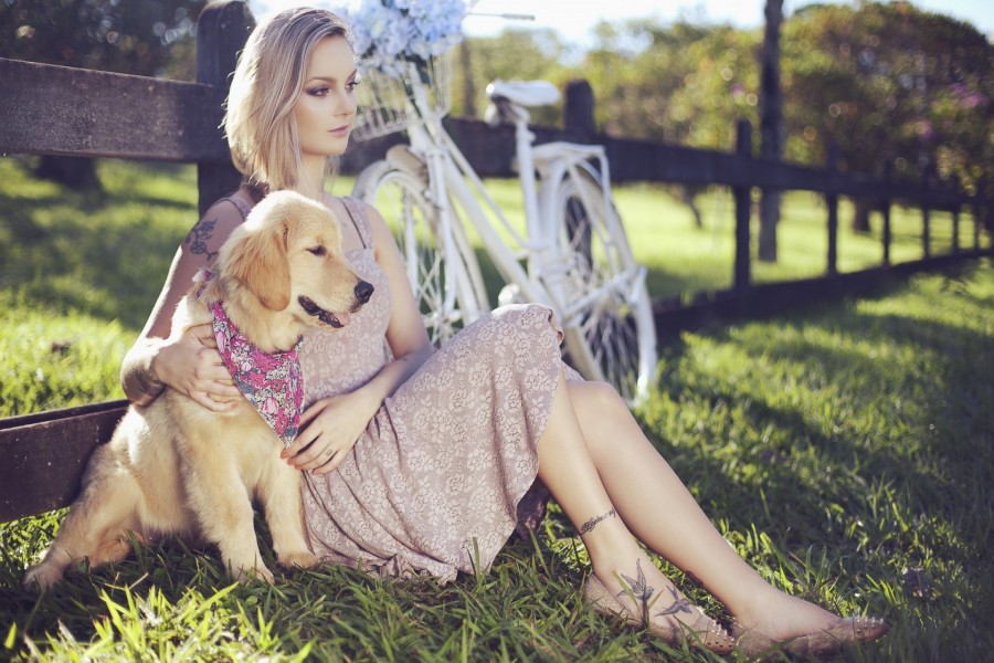 Chica sentada en la hierba junto a un perro
