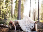Mujer tumbada sobre un tronco del bosque
