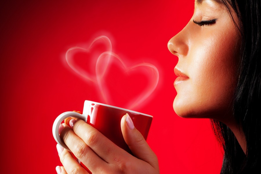 Mujer sosteniendo una taza con vapor en forma de corazones