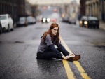 Chica enfadada sentada en una carretera