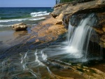 Agua cristalina cayendo al mar entre las rocas