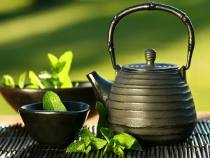 Tetera negra asiática con hojas de té y menta