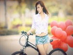 Chica transportando globos en una bici