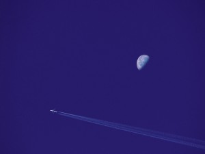 Un avión de pasajeros volando en el cielo nocturno con Luna