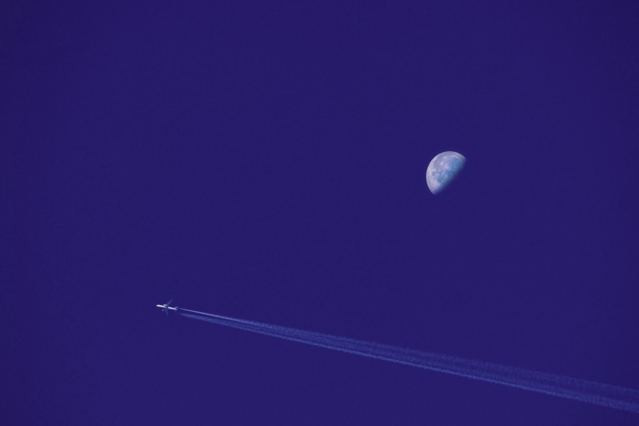 Un avión de pasajeros volando en el cielo nocturno con Luna