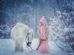Una niña con su caballo blanco en la nieve