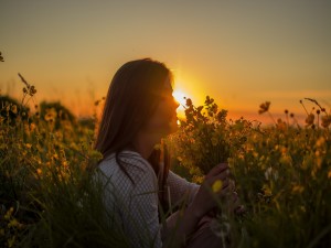 Mujer con un ramo de flores amarillas a la entrada del sol