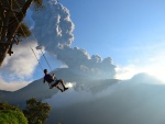 Hombre en un columpio con vistas al volcan en erupción