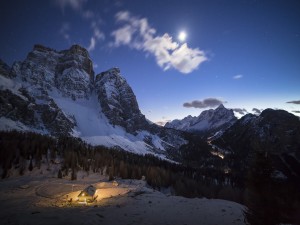 Postal: Cabaña iluminada al pie de la montaña