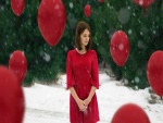 Una mujer con un vestido rojo rodeada de globos rojos