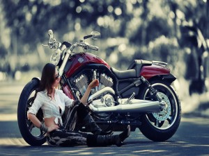 Chica sentada junto a una Harley Davidson