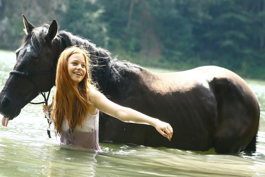 Una mujer y su caballo caminando en el agua