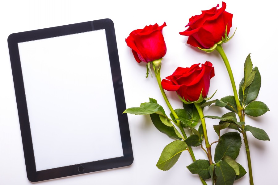 Una tablet y un ramo de rosas rojas